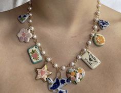 a close up of a woman wearing a necklace with flowers and charms attached to it