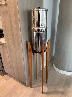 a stainless steel coffee pot on a wooden stand