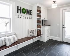 a kitchen with black tile flooring and white cabinets, along with an entryway