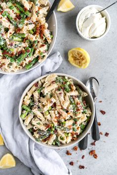 two bowls filled with pasta salad next to lemon wedges