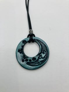 a black and blue necklace with a circular pendant hanging from it's end on a cord