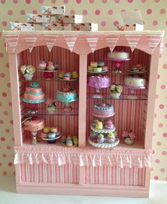 a doll house display case with cupcakes and cakes on it's shelves