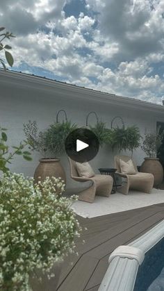 an outdoor pool with chairs and potted plants next to it on the side of a house