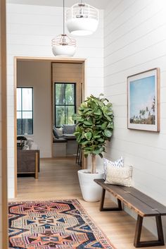 an entryway with a bench, potted plant and pictures hanging on the wall