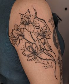 a woman's arm with flowers and vines on the back of her shoulder,