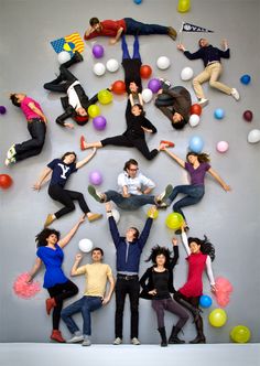 a group of people jumping in the air with balloons all around them