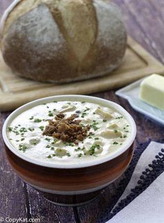 a bowl of soup sitting on top of a wooden table next to a loaf of bread