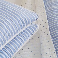 two blue and white striped bedspreads next to each other on top of one another