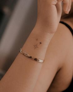 a woman is holding her hand up to her face with a small star tattoo on the wrist