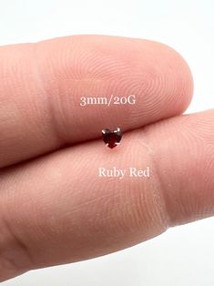 a tiny red diamond sitting on top of someone's finger