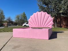 a large pink shell shaped bed sitting on top of a sidewalk