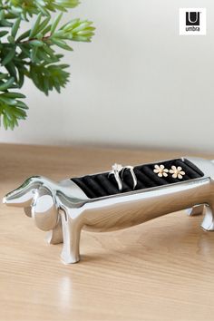 a silver vase with flowers in it sitting on a wooden table next to a plant