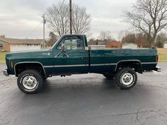 a green pick up truck parked in a parking lot