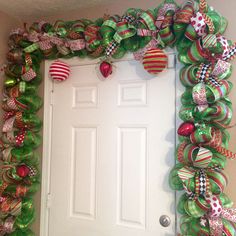 a door decorated with green and red christmas balls, bows and ornaments on the front