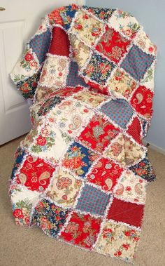 a red, white and blue patchwork quilt sitting on the floor next to a door