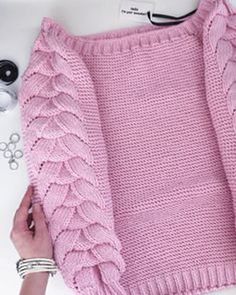 a pink sweater with ruffles is being worked on by a woman's hands