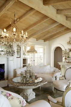 a living room filled with furniture and a chandelier hanging from the ceiling in front of a fire place