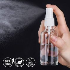 a hand holding a spray bottle that is spraying water on the surface with black background