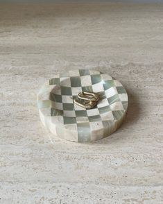 a ring dish sitting on top of a marble counter next to a white wall and floor