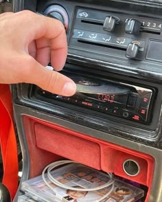 a hand is pressing the buttons on a car radio