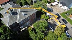 an aerial view of a house being worked on by a crane in the foreground