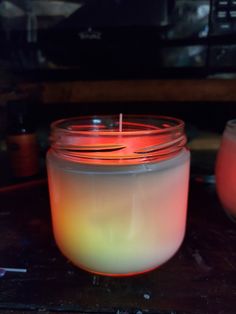 a lit candle sitting on top of a table next to some jars filled with candles