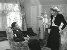 a woman standing next to a man sitting in a chair