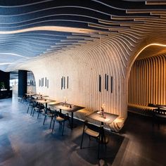 the interior of a restaurant with long tables and chairs in front of an arched wooden wall