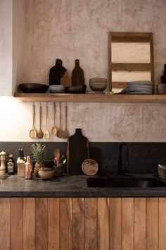 a kitchen with wooden cabinets and black counter tops, pots and pans on the shelves