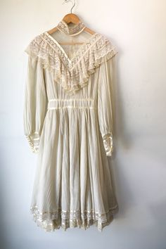 Vintage Gunne Sax Cream Lace Dress. Has one repair at back zipper and a few stains. Long sleeve lace ruffle dress in crinkle woven with double layer skirt. High neck detail in mesh with lace overlay. Has zipper and button closure at back. 65% Polyester 35% Cotton with nylon lace, hand wash cold. Marked as size 13, fits M/L best.  Approx. Measurements: Underarm to Underarm: 19 1/2"  Waist: 15 1/2" Length: 46 1/2" Cream Long Sleeve Midi Dress With Lace Trim, Cream Long Sleeve Dress With Lace Collar, Daywear Midi Dress With Lace Collar, Daywear Lace Midi Dress With Lace Sleeves, Cream Lace Patchwork Dress For Daywear, Lace Midi Dress With Lace Sleeves For Daywear, Daywear Victorian Lace Dress With Ruffles, Daywear Lace Victorian Dress With Ruffles, Spring Vintage Lace Dress With Ruffles