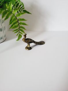 a snake figurine next to a potted plant on a white table top