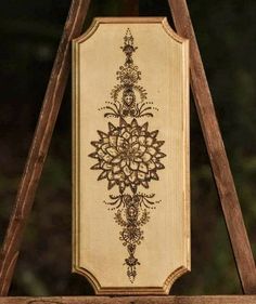 a wooden sign with an ornate design on it's side hanging from a wood frame