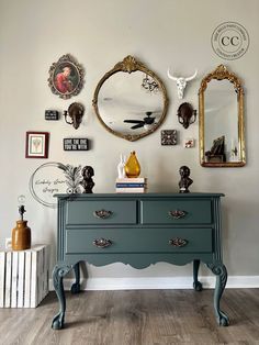 an old dresser is painted green with gold accents and mirrors on the wall above it