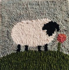 a sheep hooked up to the side of a rug with grass and flowers on it