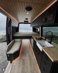 an interior view of a camper with the kitchen and living area in it, looking out onto the ocean