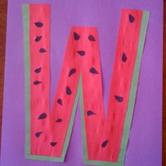 the letter w made out of watermelon paper on a purple sheet of paper