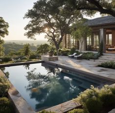 an outdoor pool surrounded by greenery and trees with the sun shining on it's horizon