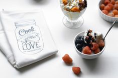 a bowl of fruit and yogurt next to a napkin with the words cook where you love on it