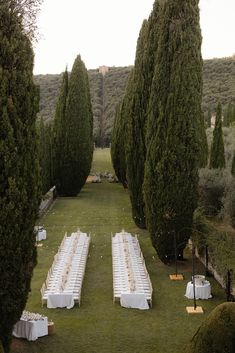 an outdoor wedding setup with white linens and gold place settings in the middle of trees