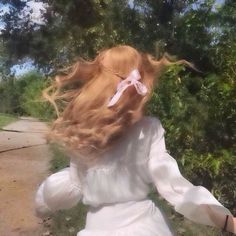 a woman with long red hair walking down a path