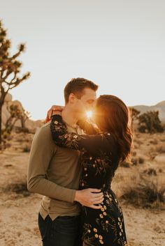 a man and woman kissing in the desert with sun shining through their eyes as they stand close to each other