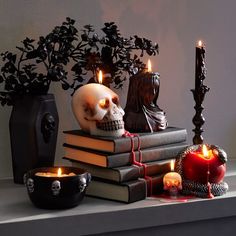 a table topped with books and candles next to a skull head on top of it