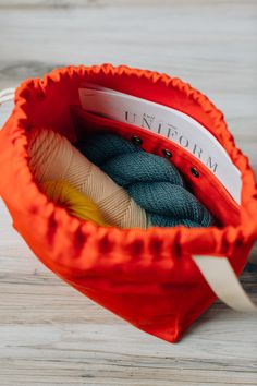 an orange bag filled with yarn sitting on top of a wooden floor