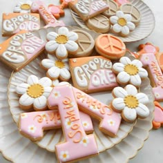 some decorated cookies on a plate with flowers and peace signs in the middle one is pink