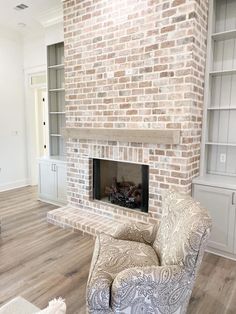 a living room with a brick fireplace and white furniture