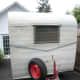 an old trailer is parked in front of a house with a red wheel on it