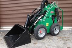 a green skid steer parked in front of a garage door