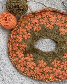 an orange and green knitted bag with yarn next to it