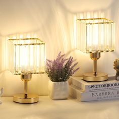 two lamps sitting next to each other on top of a white table with purple flowers