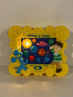 a small yellow frame with a cartoon character on the front and sides, holding an object in it's hand